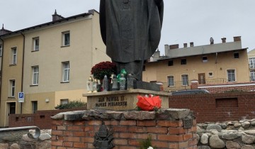 Pomnik Jana Pawła II z kwiatami - powiększ
